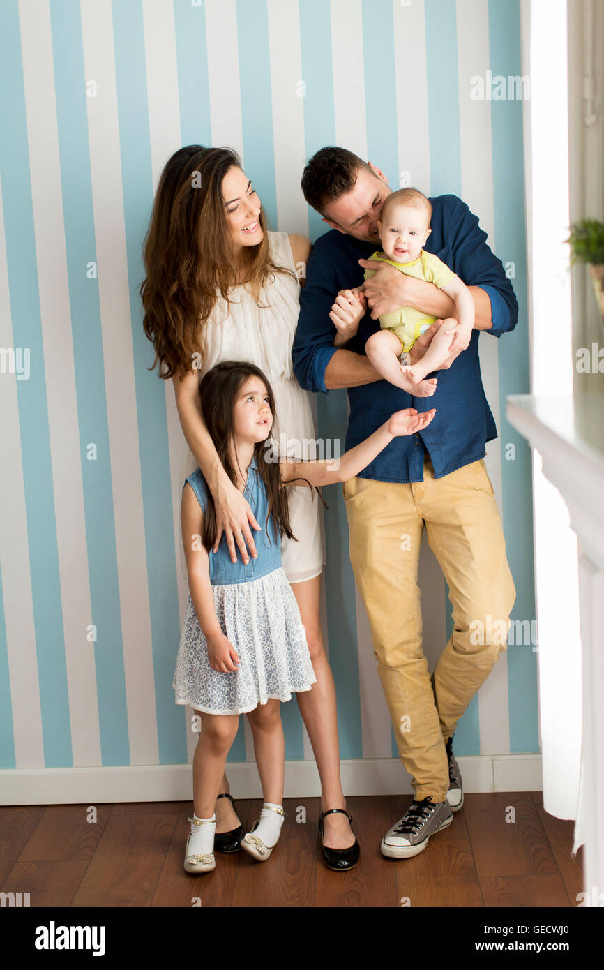 Young family standing side by side by the wall Stock Photo