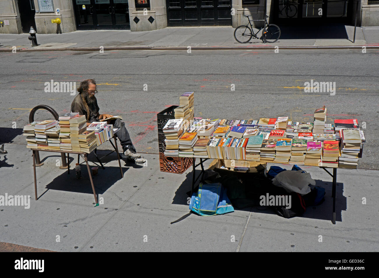 A middle aged man with a beard selling used books on West 4th Street in Greenwich Village near New York University. Stock Photo