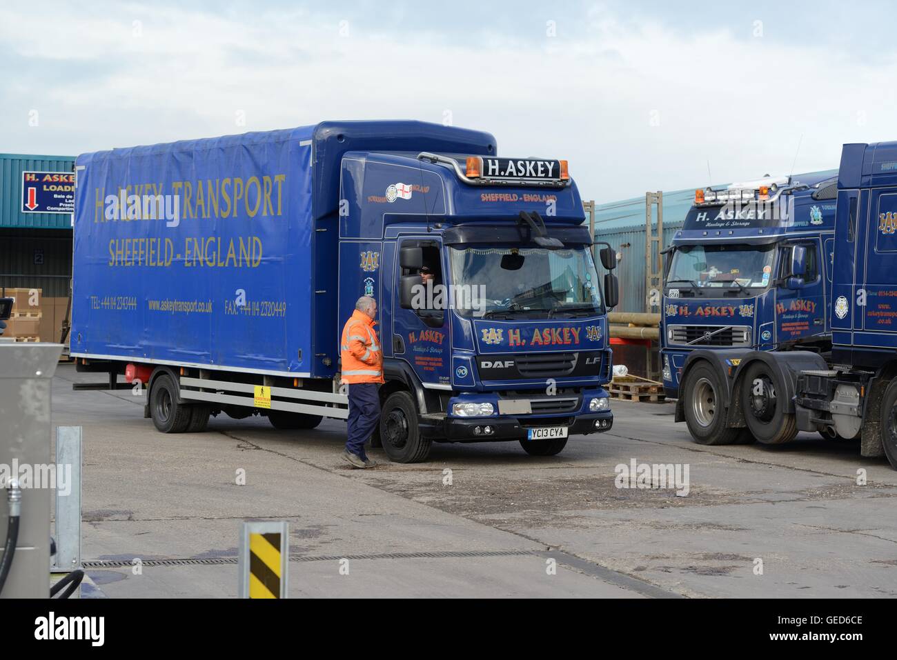 Driver in a truck cab talking to the yard man in a haulage firm yard Stock Photo