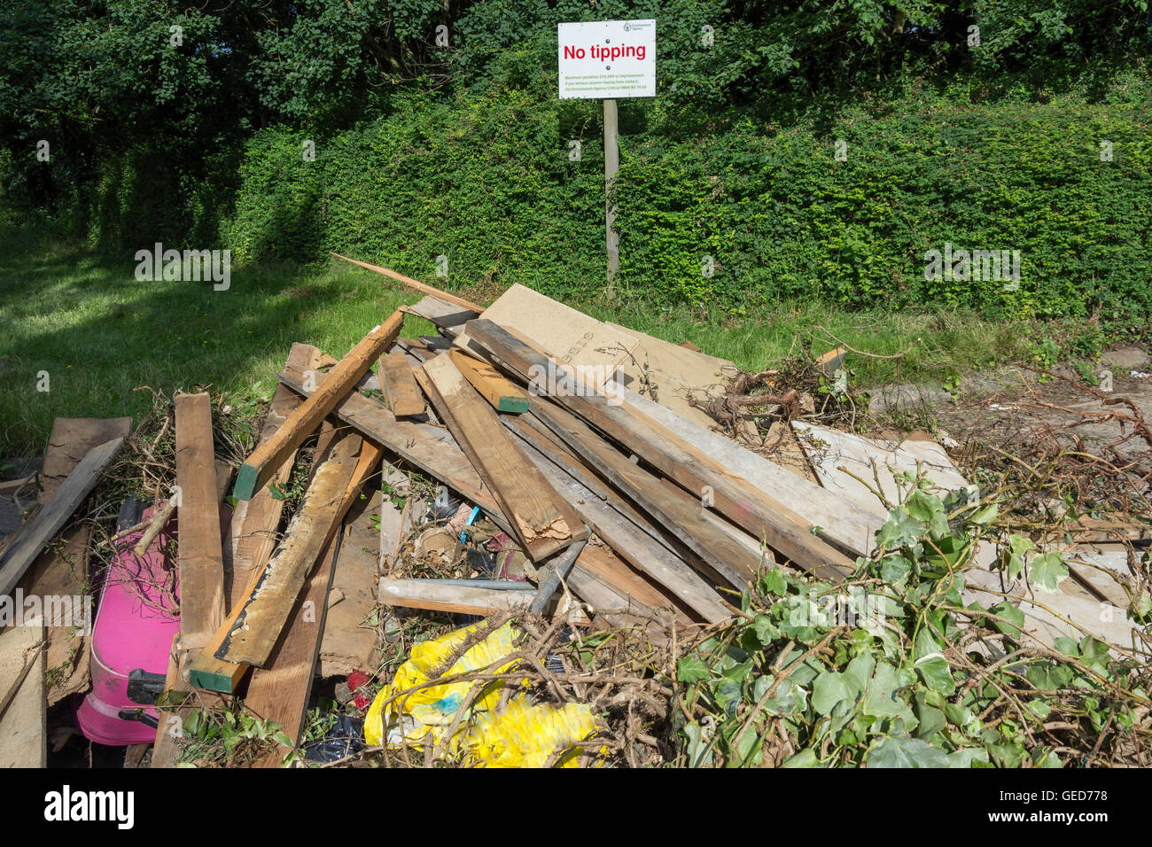 Pile of rubbish dumped at side of a road with No tipping sign, Stroude Road, Egham, Surrey, England, United Kingdom Stock Photo
