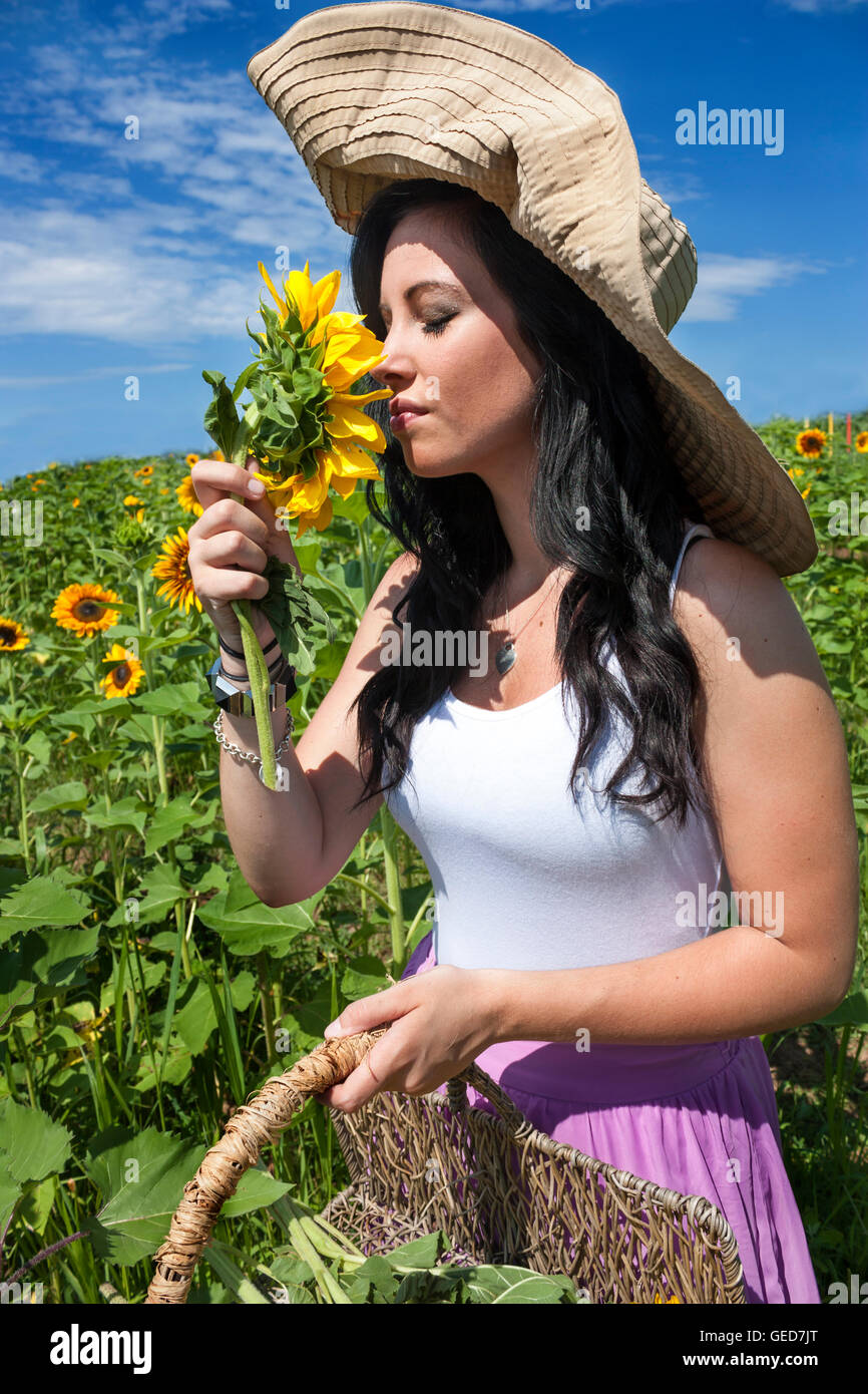 Pretty young brunette woman wearing large hat and pink skirt holding ...