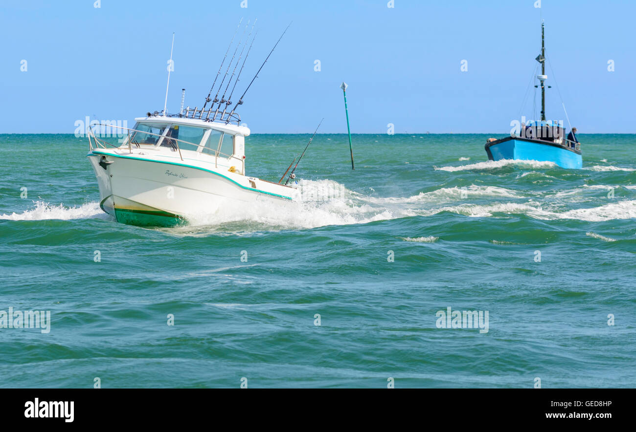 Fishing boats at sea coming towards the river estuary. Stock Photo