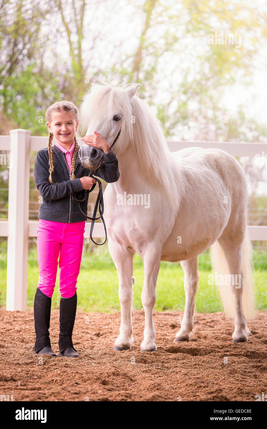 Shetland Pony. Child in riding dress standing next to gray mare. Germany Stock Photo