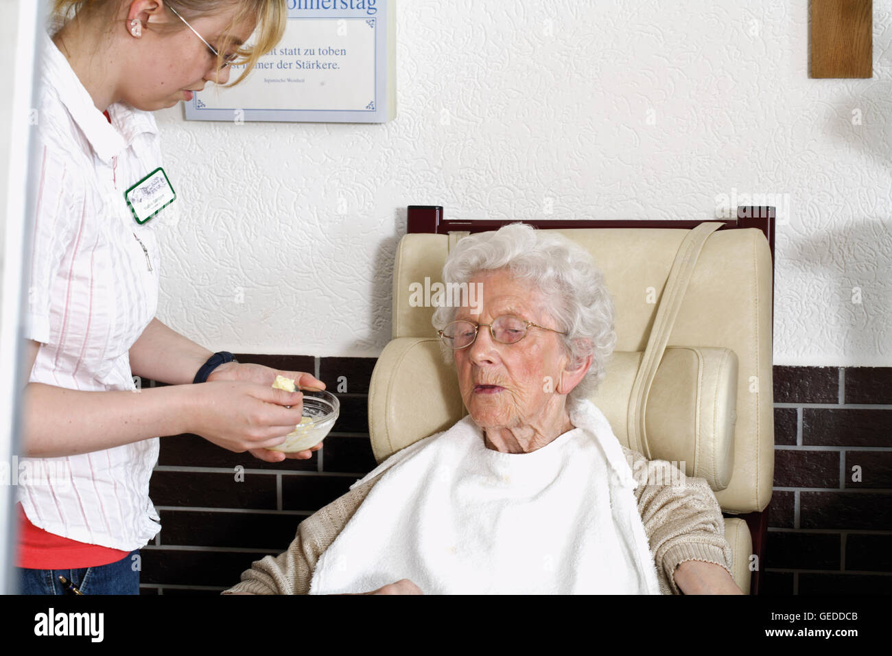 Caregiver feeding an elderly woman at a nursing home Stock Photo