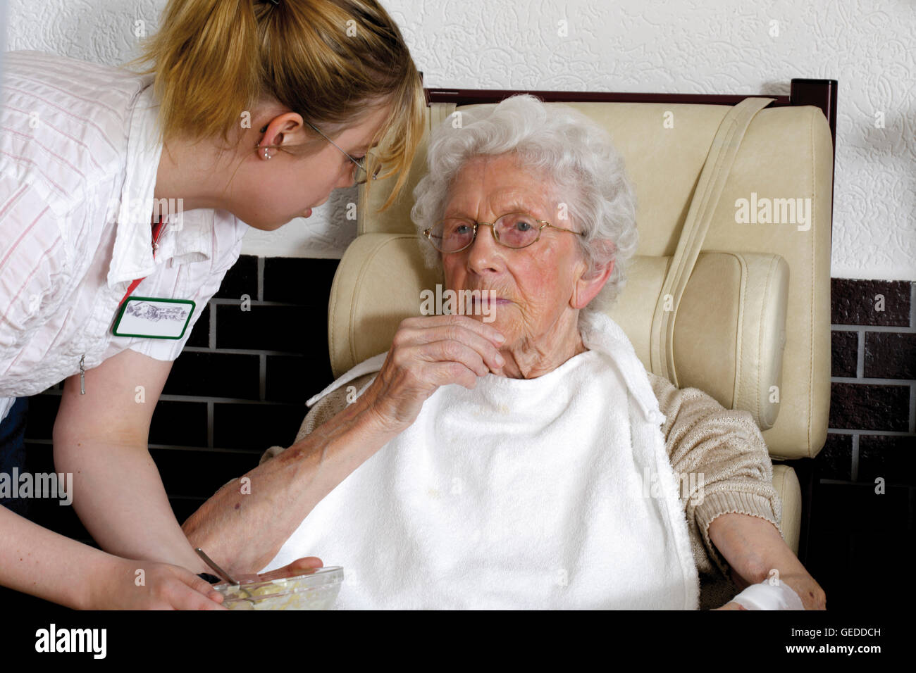 Caregiver offering affectionate care to an elderly woman at a nursing home Stock Photo