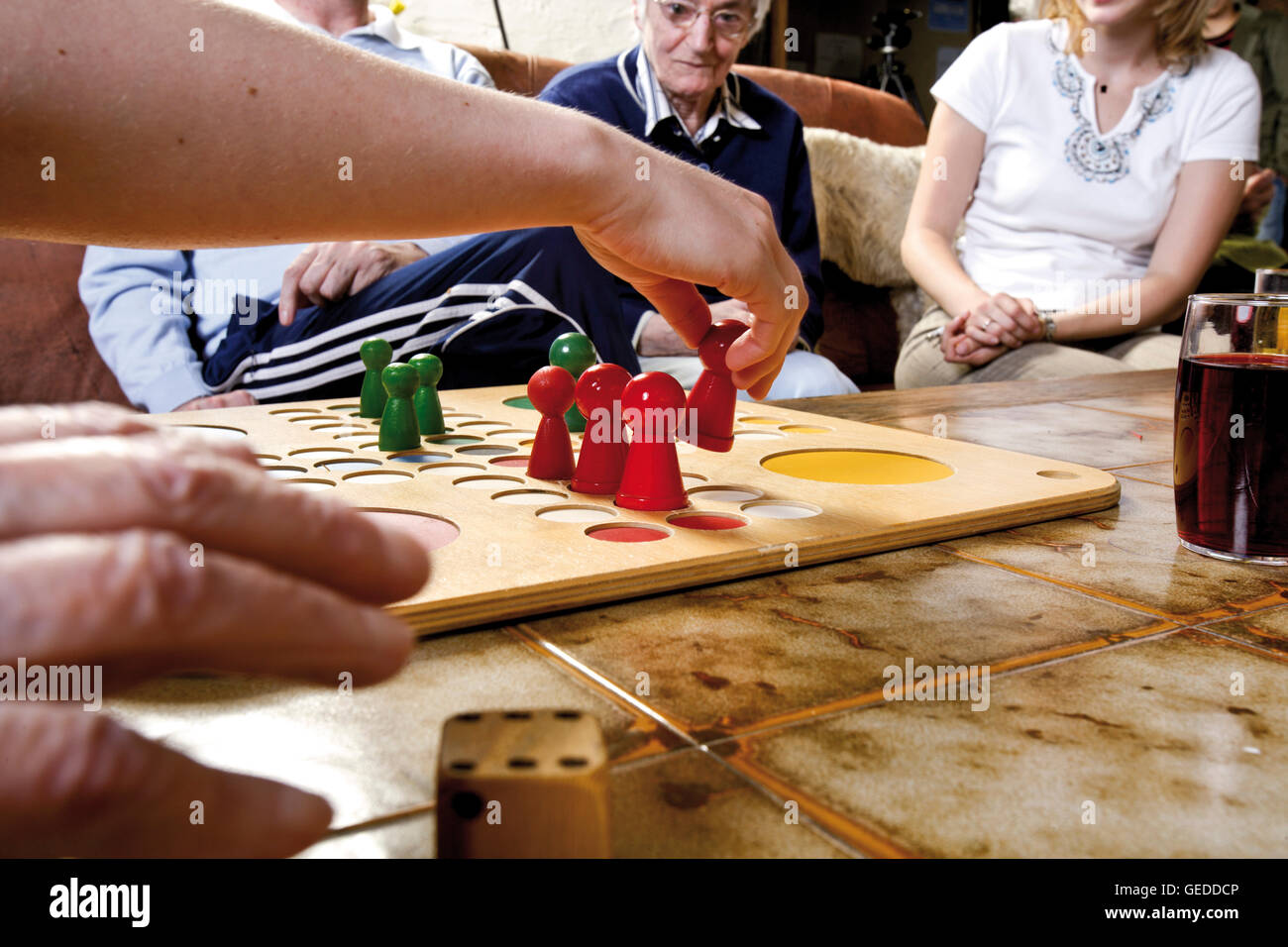 Senior citizens playing Ludo with over-sized game pieces at an old-age home Stock Photo