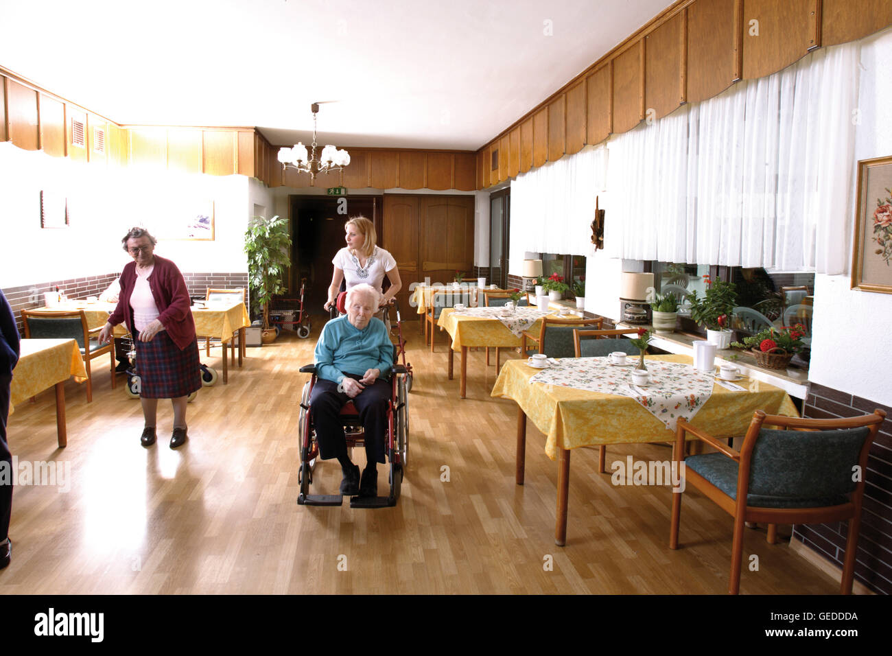 Residents being escorted into the dining hall of a nursing home Stock Photo