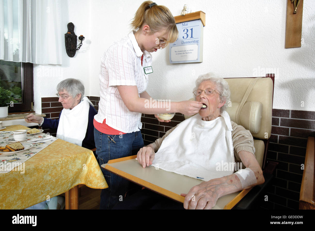 Nurse spoon feeding nursing home resident Stock Photo