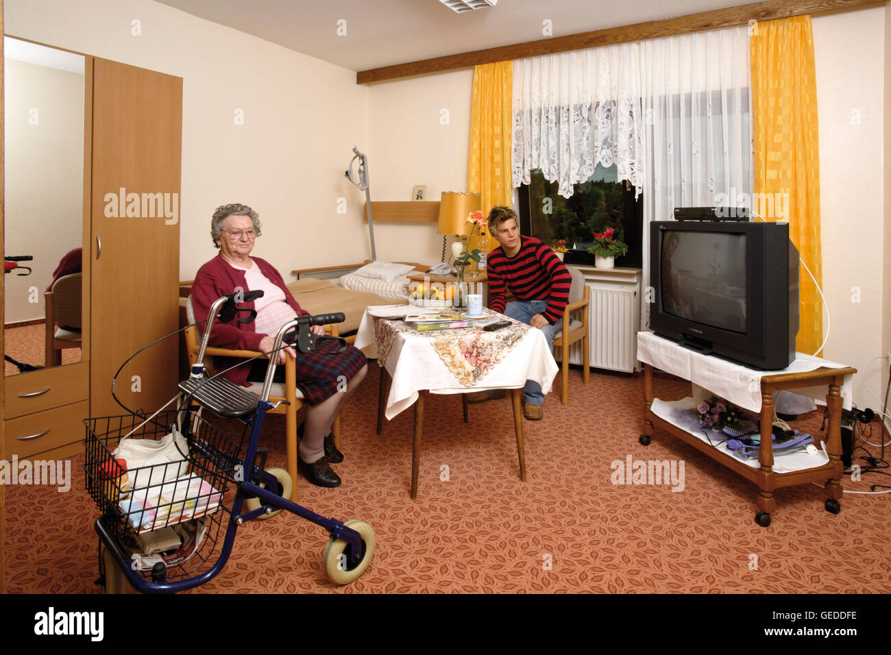 Room in an old-age home, nursing home, senior being visited by her grandson Stock Photo