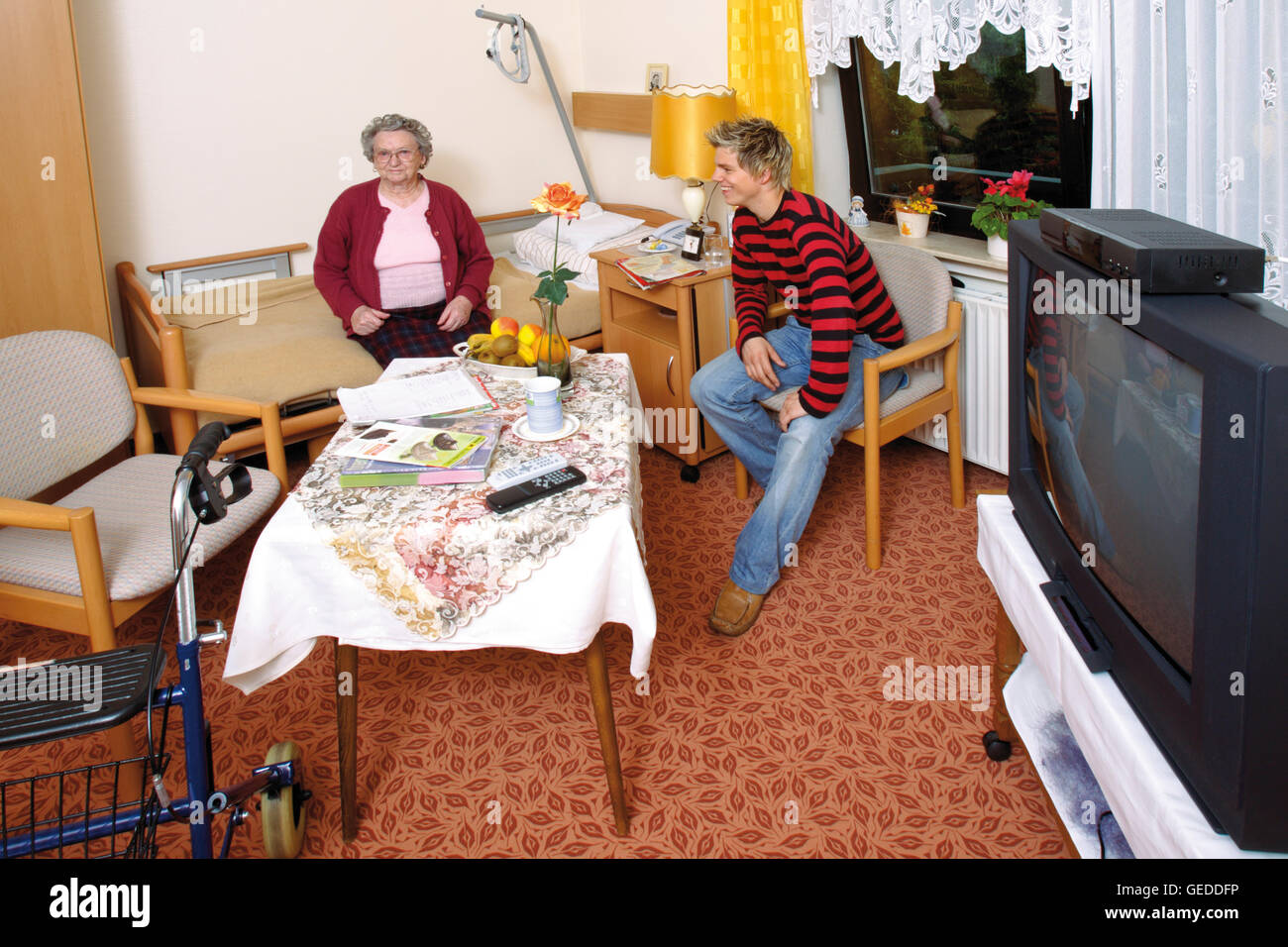 Room in an old-age home, nursing home, old woman being visited by her grandson Stock Photo