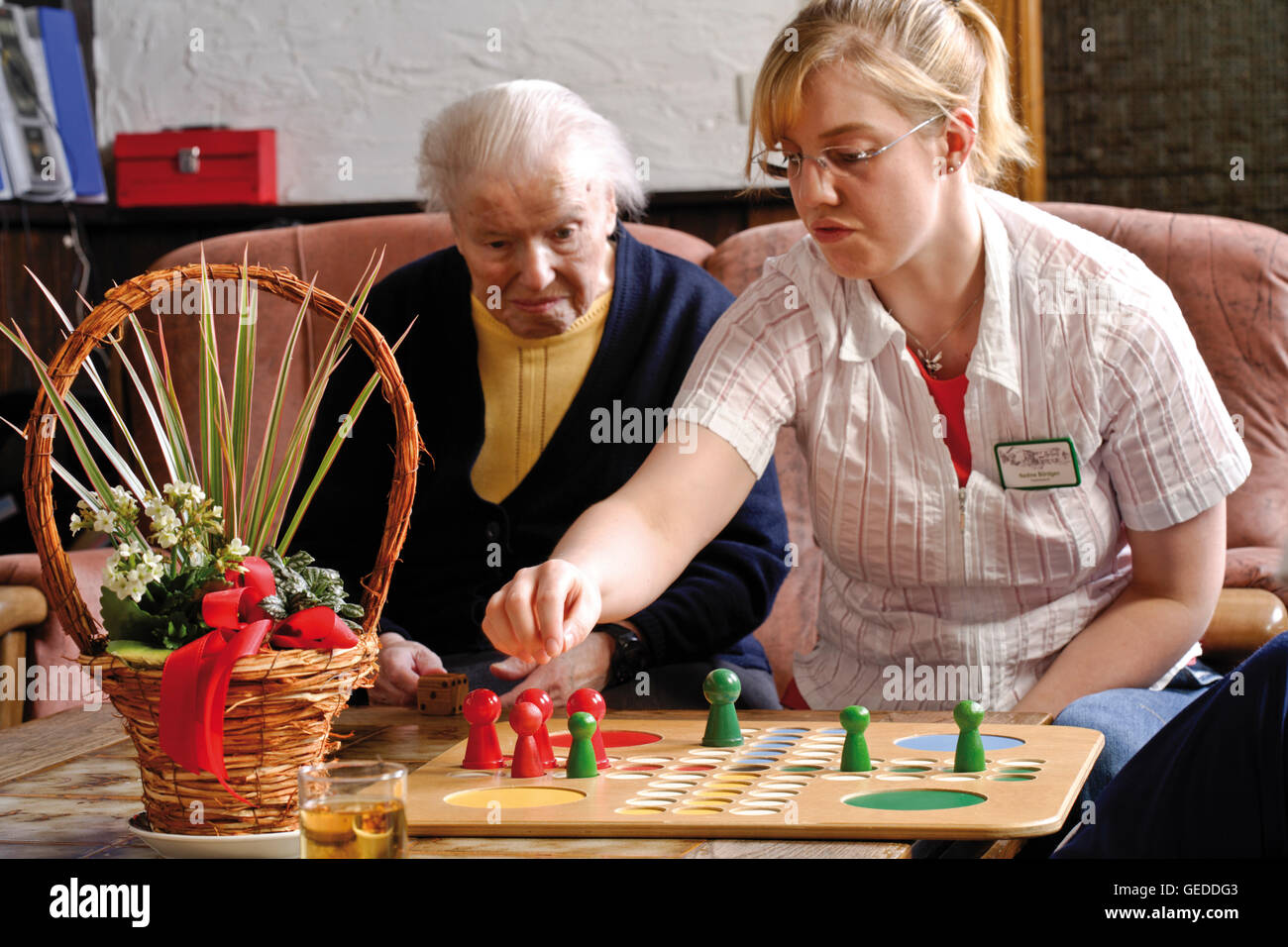 Caregiver playing a board game with an elderly lady at a nursing home Stock Photo