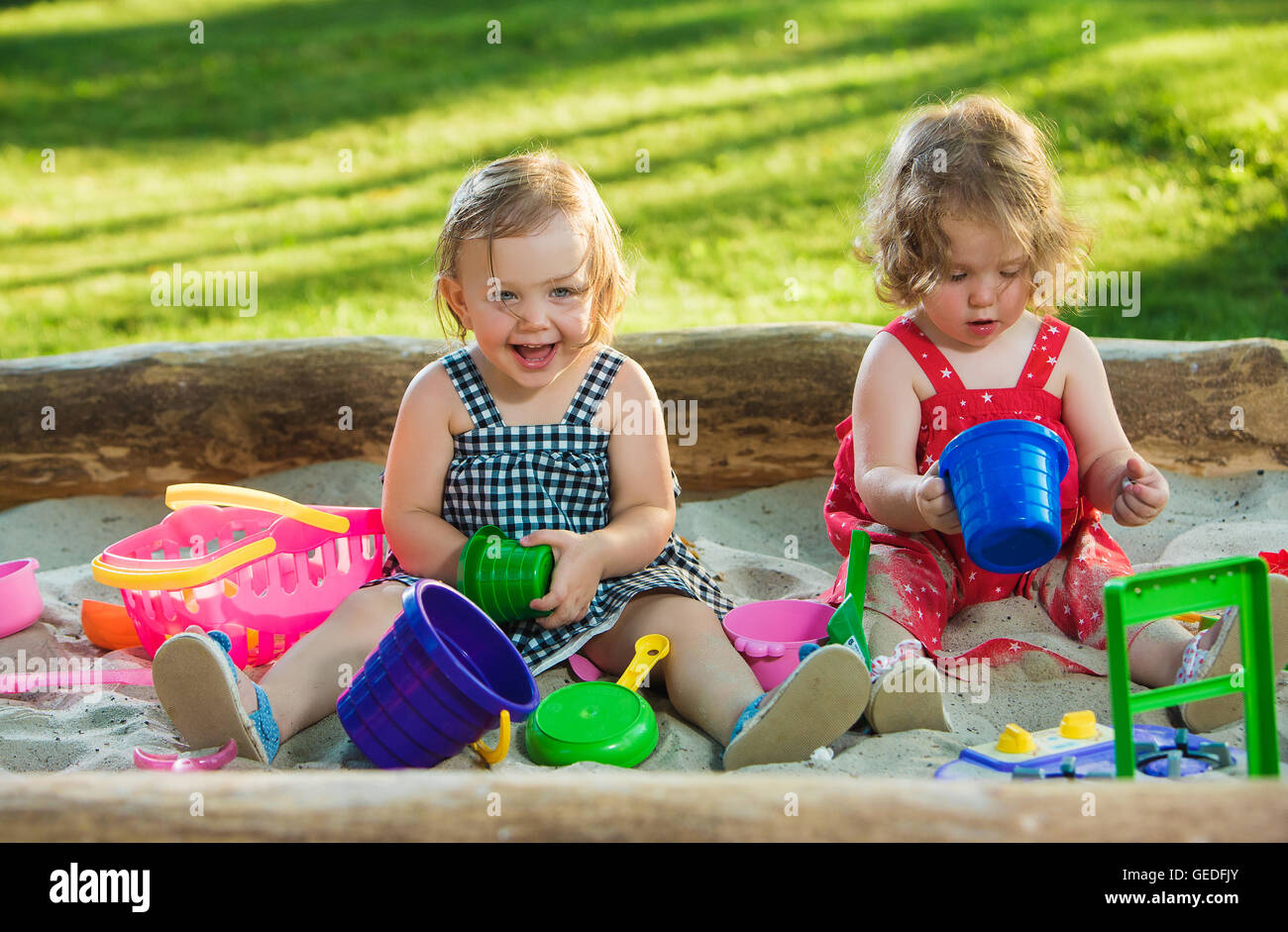 The two little baby girls playing toys in sand Stock Photo - Alamy
