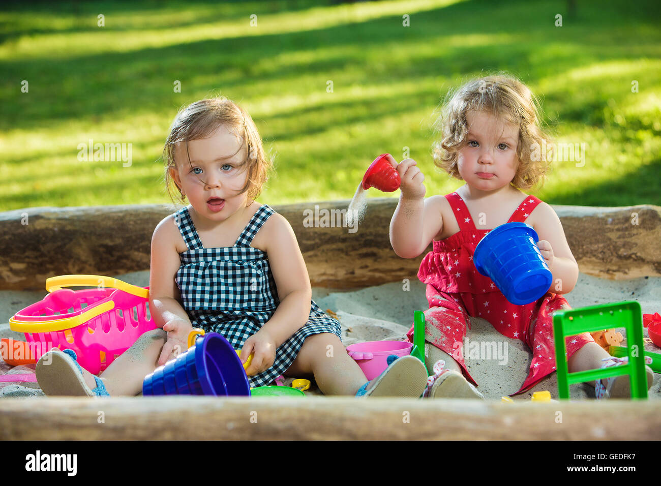 The two little baby girls playing toys in sand Stock Photo - Alamy