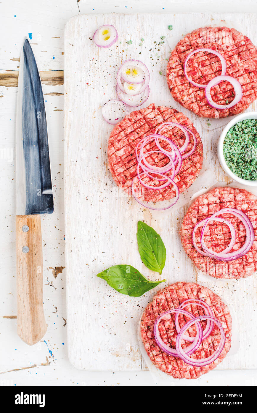 Raw ground beef meat cutlet for making burgers with onion rings, spices