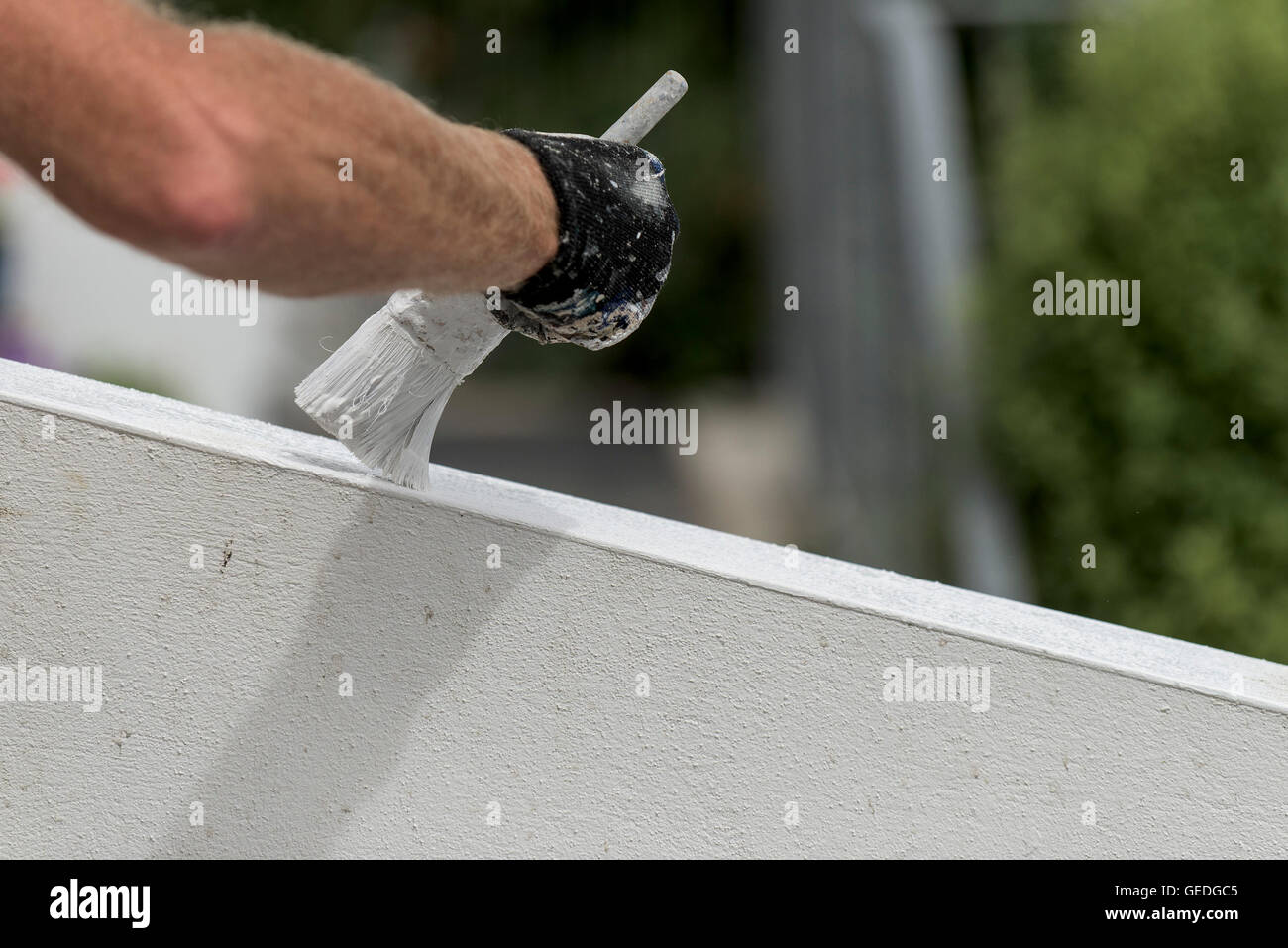 A painter and decorator painting the exterior wall of a house. Stock Photo