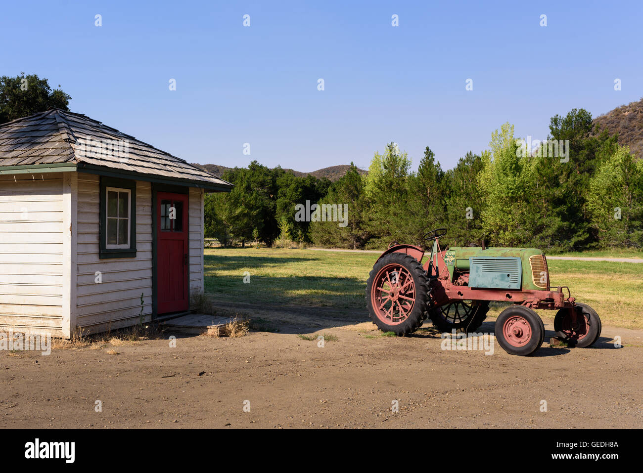 White wood farm shed with faded vintage red green tractor Stock Photo ...