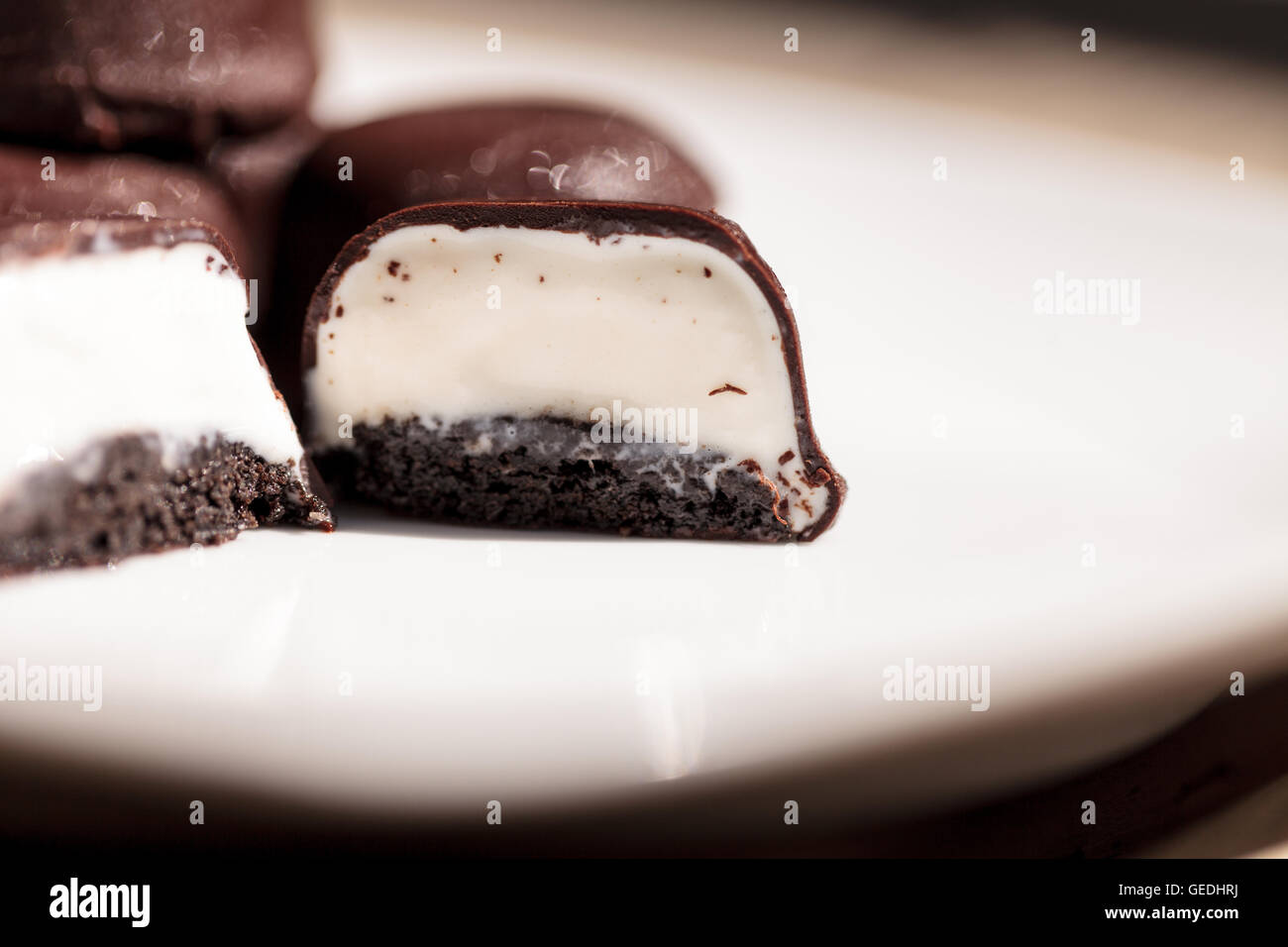 Vanilla ice cream bonbons covered in chocolate for desert on a white plate. Stock Photo