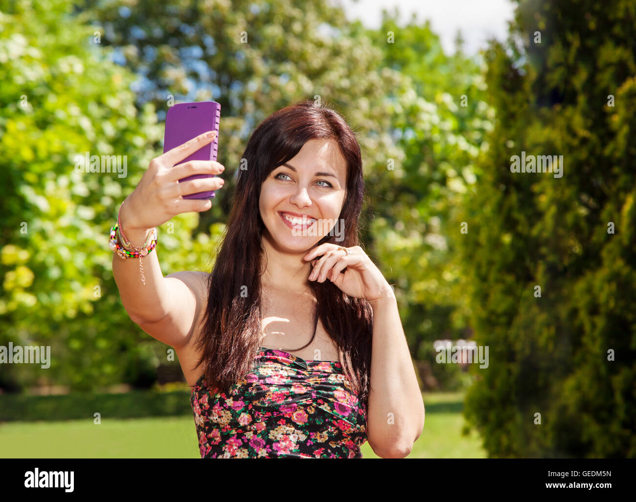 young beautiful girl doing selfie mobile phone in the park on summer ...