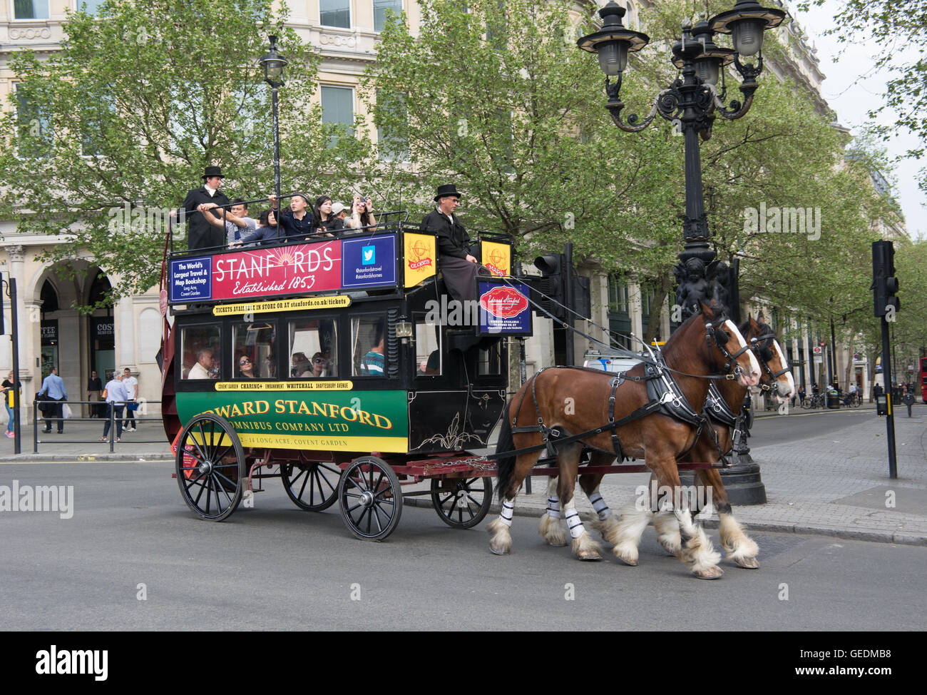 A horse drawn bus carries tourist past Trafalger Square on a tour around London operated by Edward Stanford Omnibus Company Stock Photo
