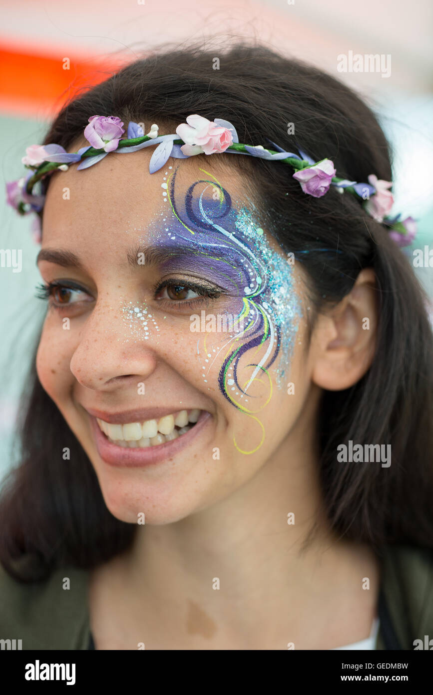 A portrait of a smiling olive skinned woman with face painting at a festival with long dark hair and a flower headband Stock Photo