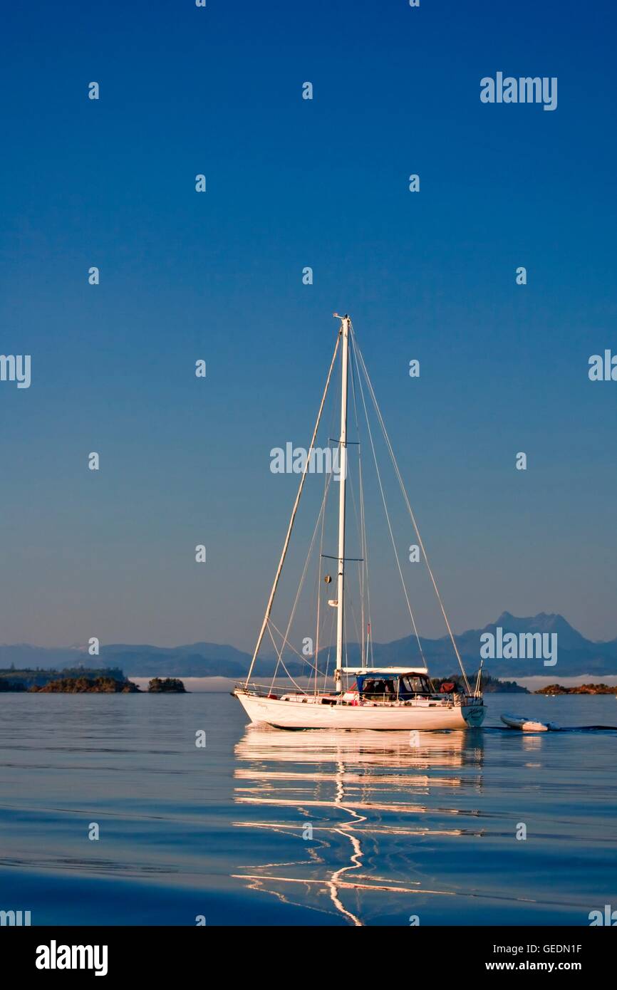 geography / travel, Canada, British Columbia, Sailboat with no sails up in Johnstone Strait near Telegraph Cove with Mount Stephens in the background. Stock Photo