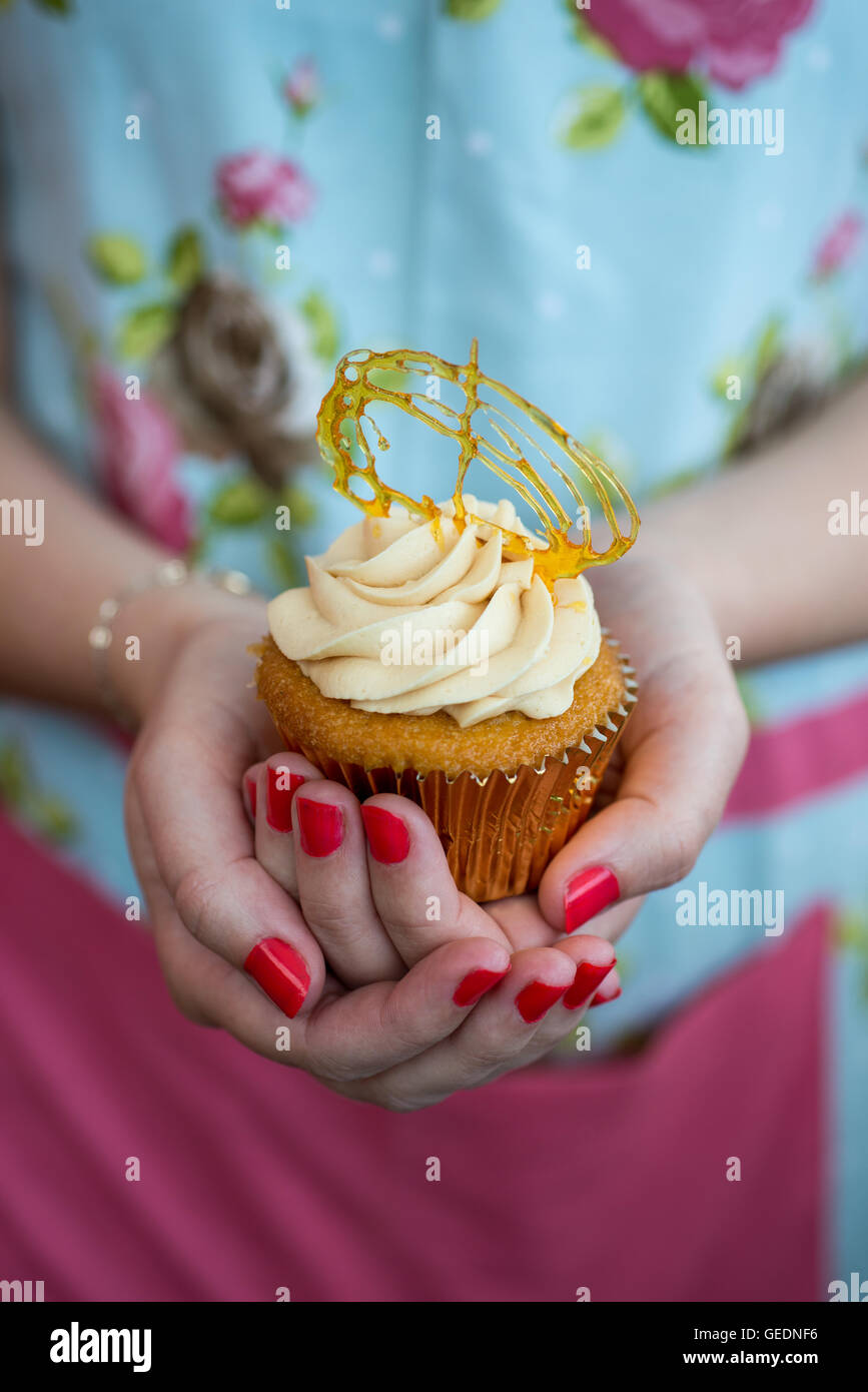 Woman S Hands Holding A Cupcake With Brownish Frosting Topped With