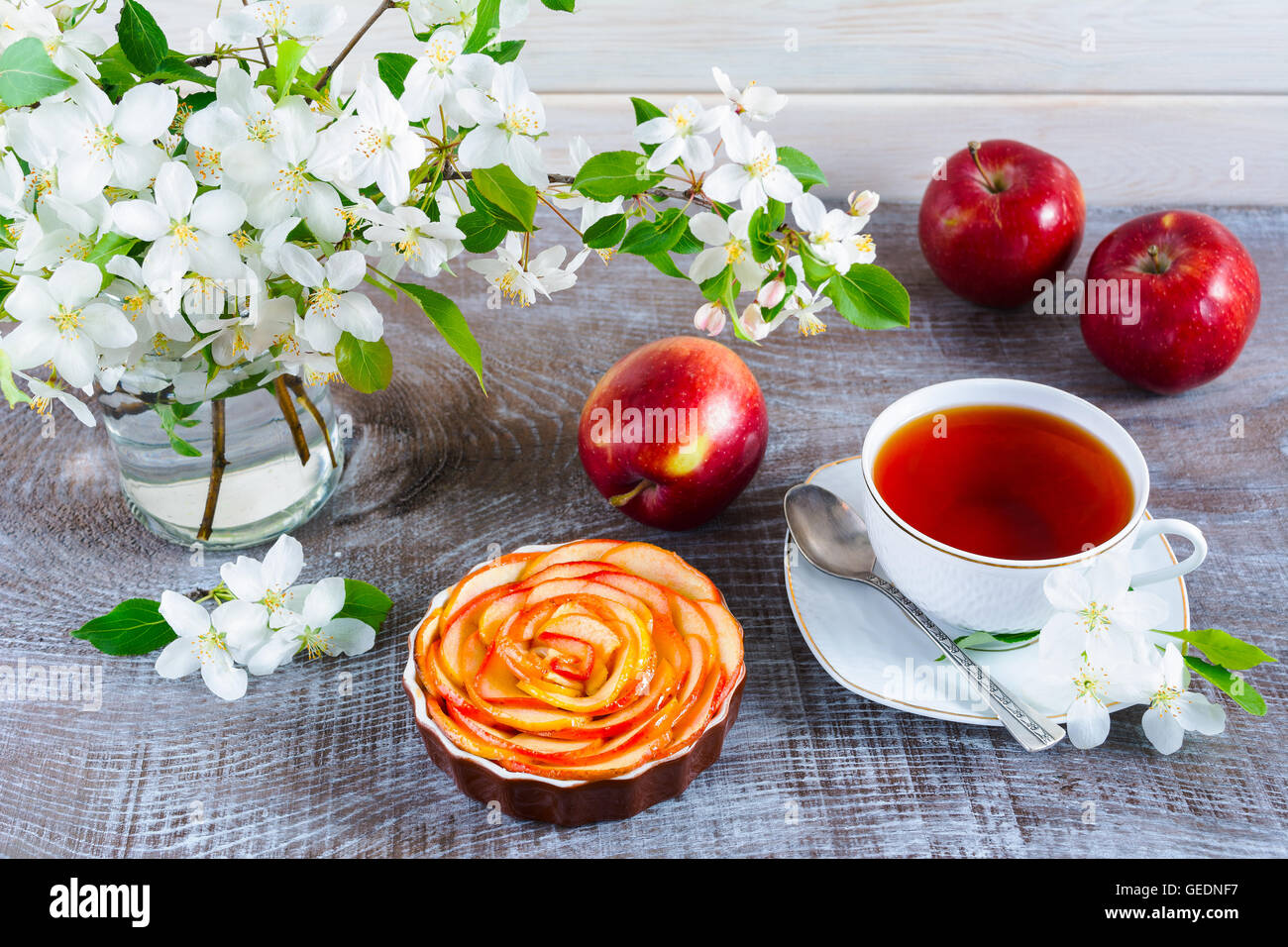 Apple rose shaped pie and cup of tea on wooden table. Homemade apple cake for tea time. Breakfast tea with sweet apple pastry. Stock Photo