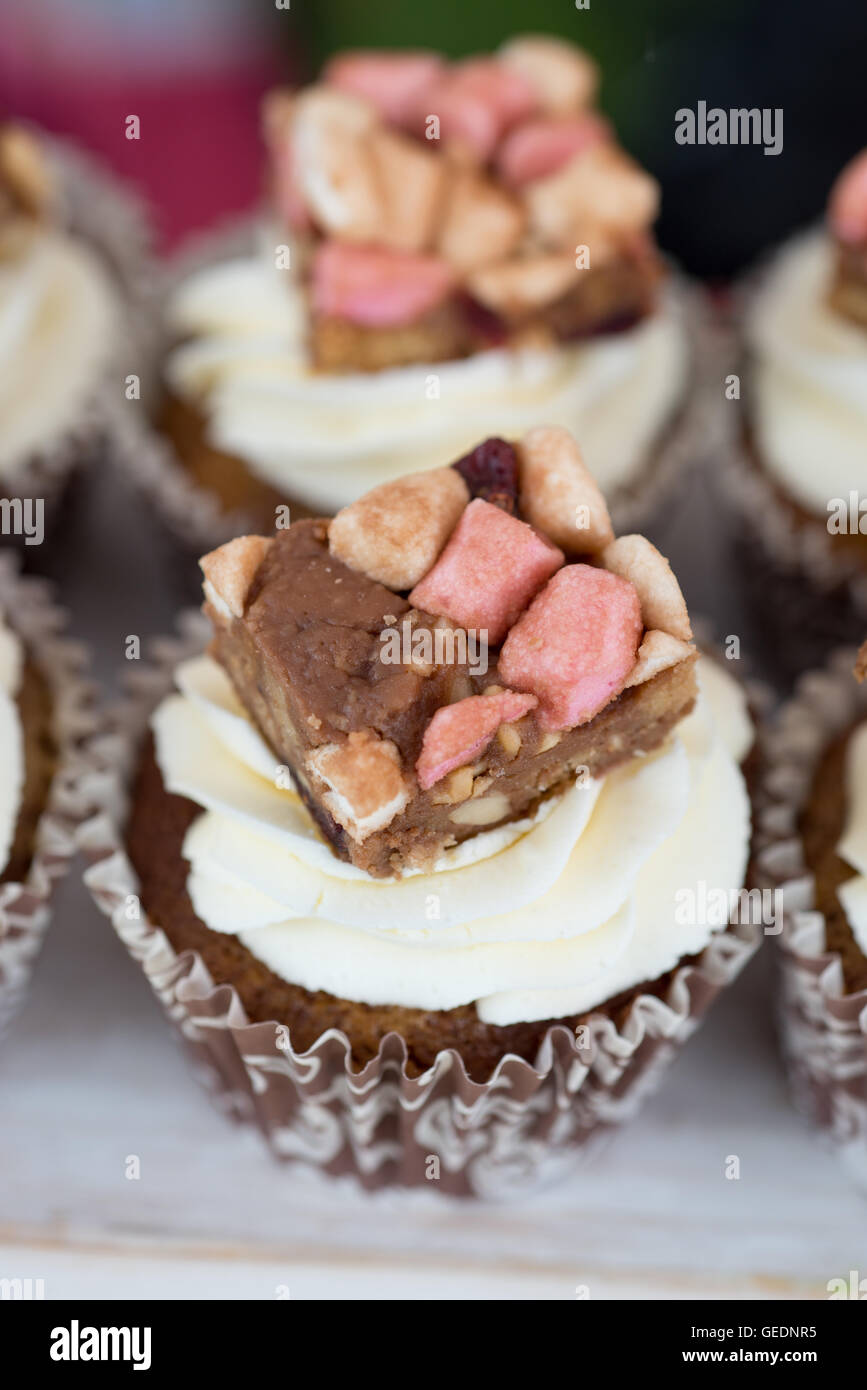 Rocky Road-flavoured cupcakes in pretty brown and white paper cases topped with icing and a slice of rocky road Stock Photo