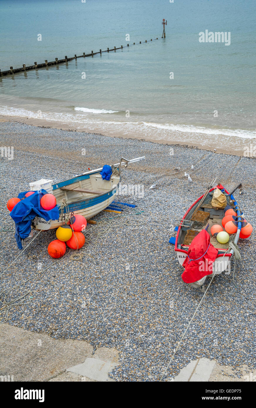 Small fishing boats beached on the pebble beach at Sheringham, Norfolk, England, U.K. Stock Photo
