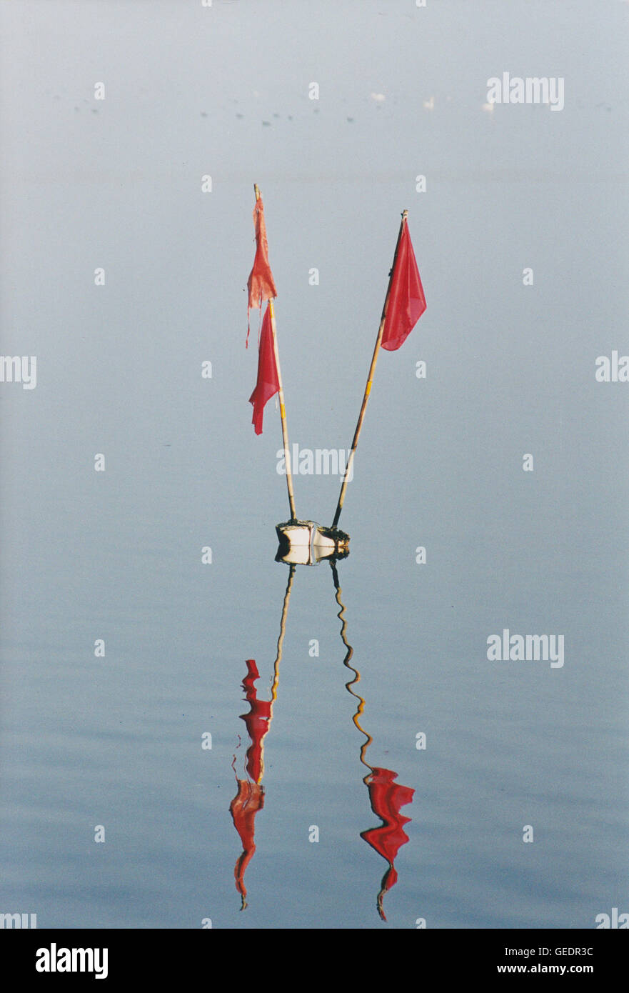 Marking flags of fishing net mirror in the water and forms a X Stock Photo