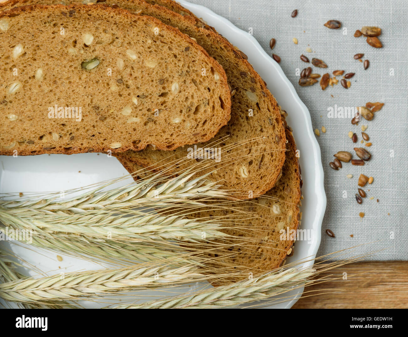 Fresh crusty bread on the plate and wheat ears on a wooden table Stock Photo