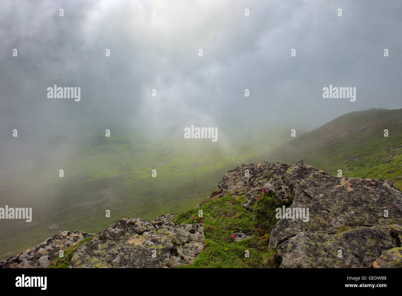large flat stone relief in the foreground at dawn. Carpathian mountains. dramatic fog after thunderstorm. Stock Photo