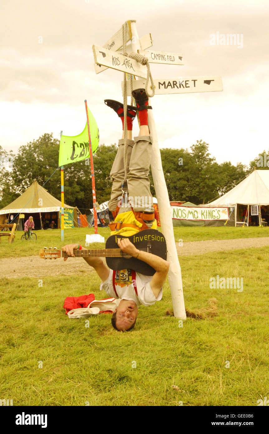 A man playing guitar while hanging upsidown at the Big Green Gathering, UK August 2005 Stock Photo