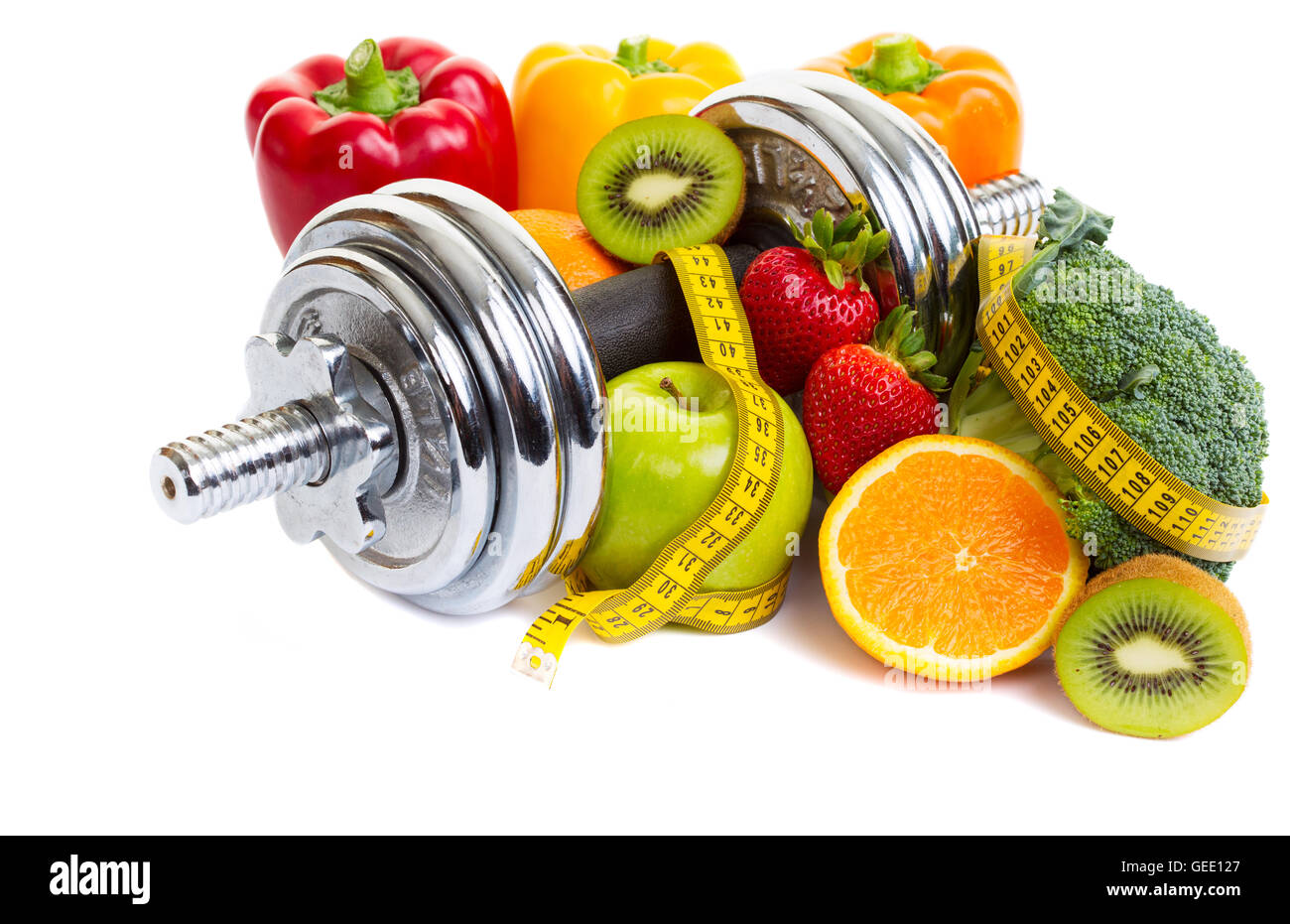 Chrome dumbbells surrounded with healthy fruits and vegetables studio shot on a white background with shadows. Stock Photo