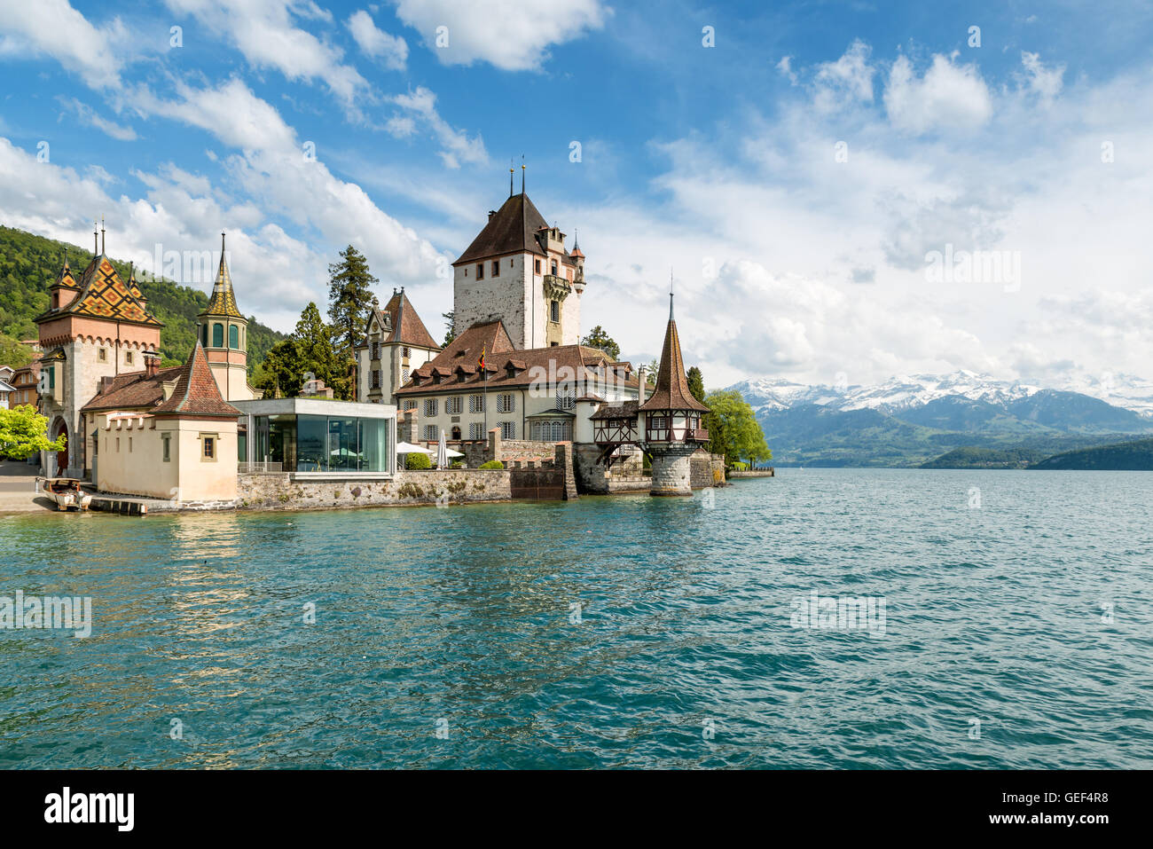 Beautiful little tower of Oberhofen castle in the Thun lake with mountains on background in Switzerland, near Bern. Stock Photo