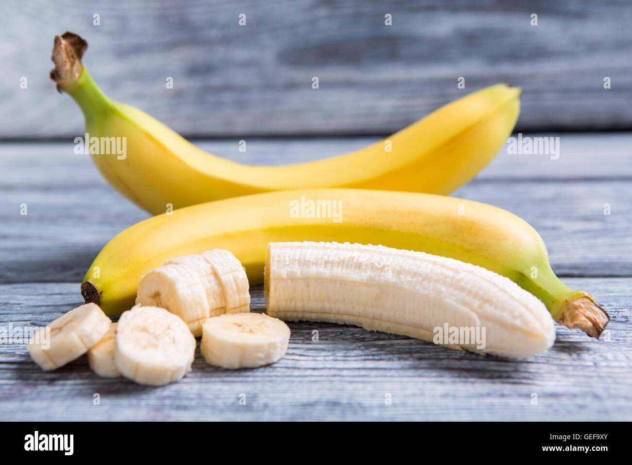 Peeled and sliced banana. Bananas on gray wooden backround. Sweet food high in calories. Fruit