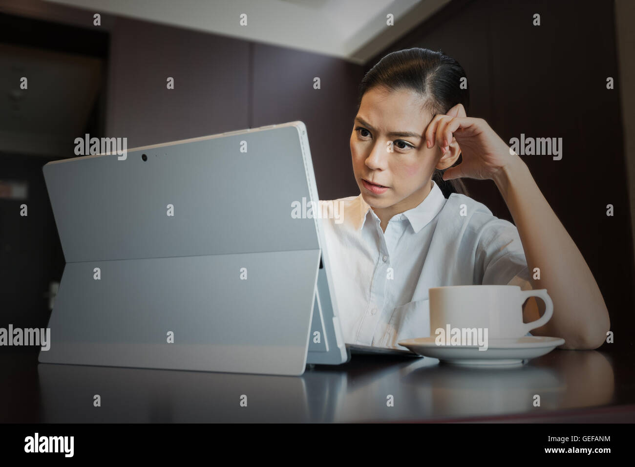 Frustrated businesswoman having headache hold hand head bite lips upset while working using tablet Laptop Computer, work failure Stock Photo