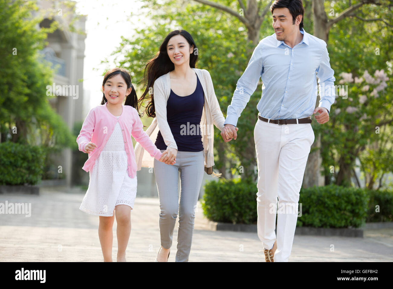 Happy young Chinese family holding hands running Stock Photo - Alamy