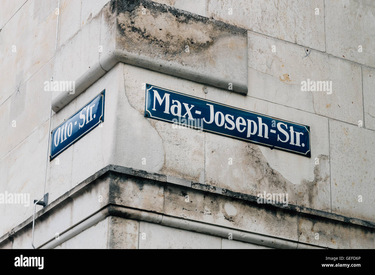 Street name signs in a corner of Munich on a stone wall. Stock Photo