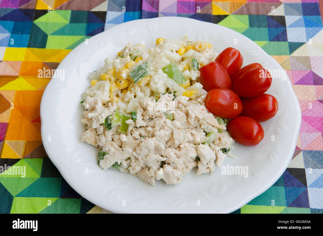 Plated steam chicken salad with tomatoes, cauliflower and corn on a multicoloured background Stock Photo