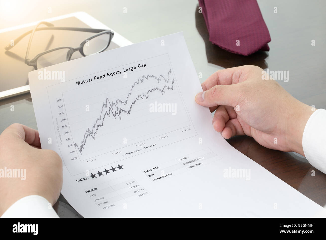 Businessman review  his mutual fund return and benchmark graphs and mutual fund rating. Mutual fund information with pen. Stock Photo