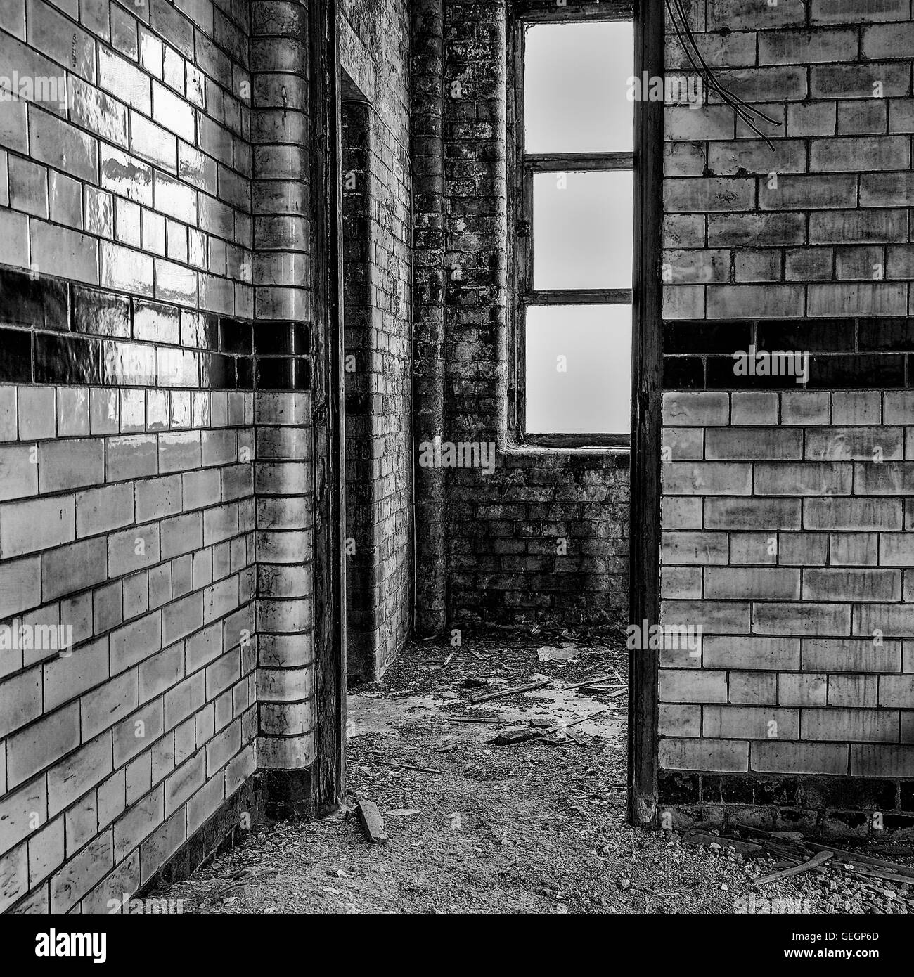 Black & White image of a white tiled room with no tables or chairs with debris on thr floor. Stock Photo