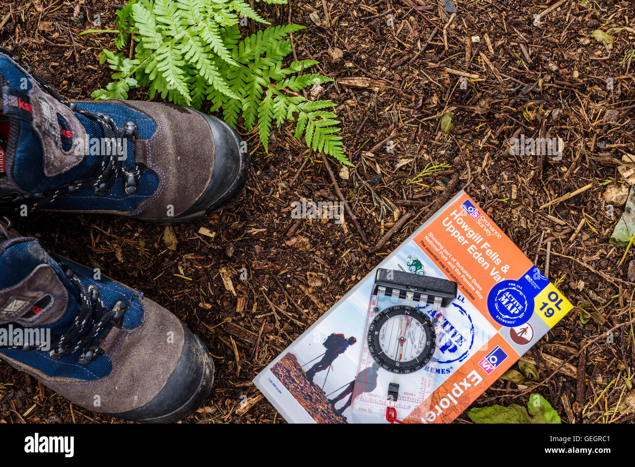 Pair of walking boots with a map and compass, on a woodland floor. Aerial view, from above. Stock Photo