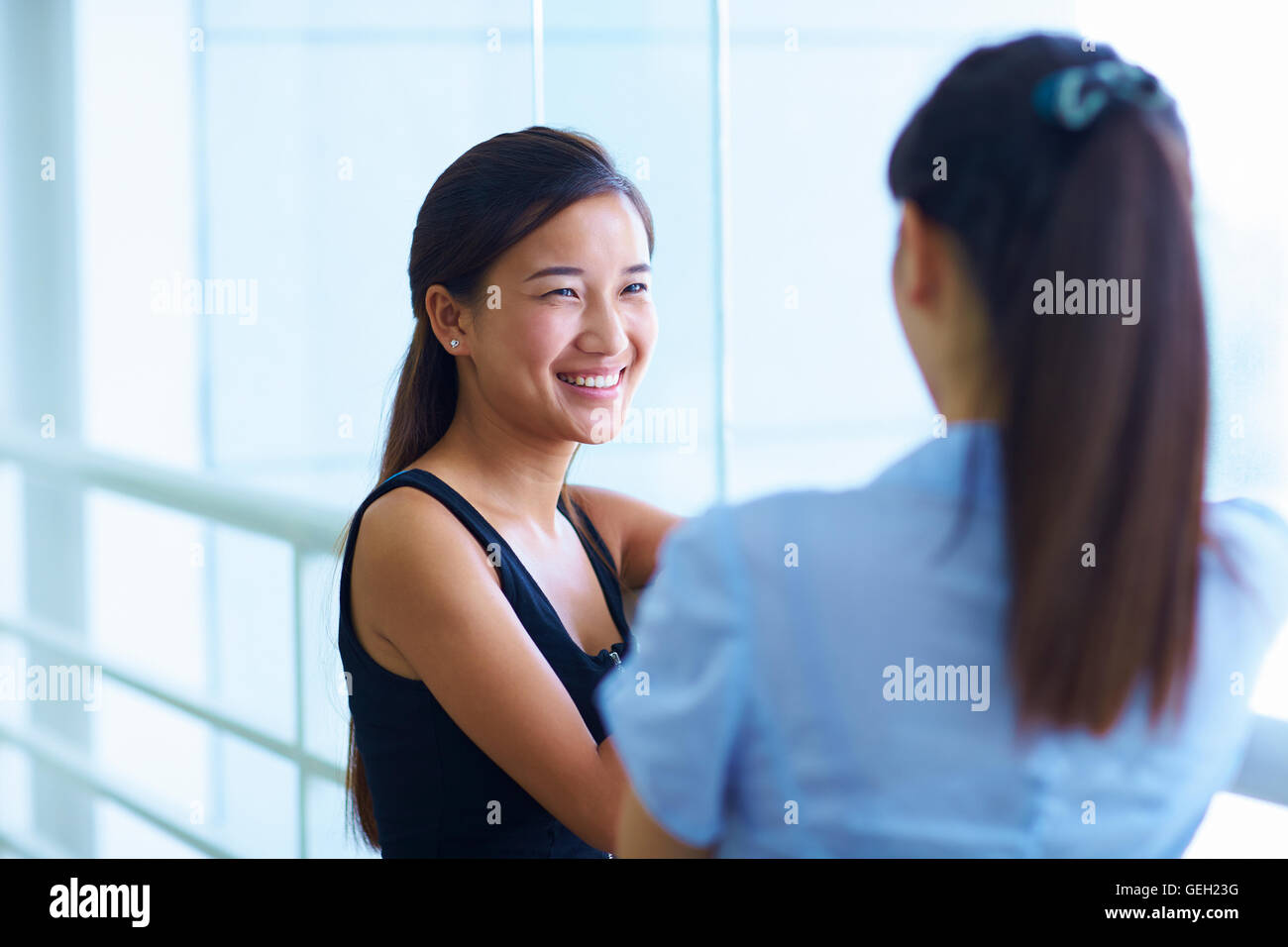 two young Asian woman talking in the library Stock Photo