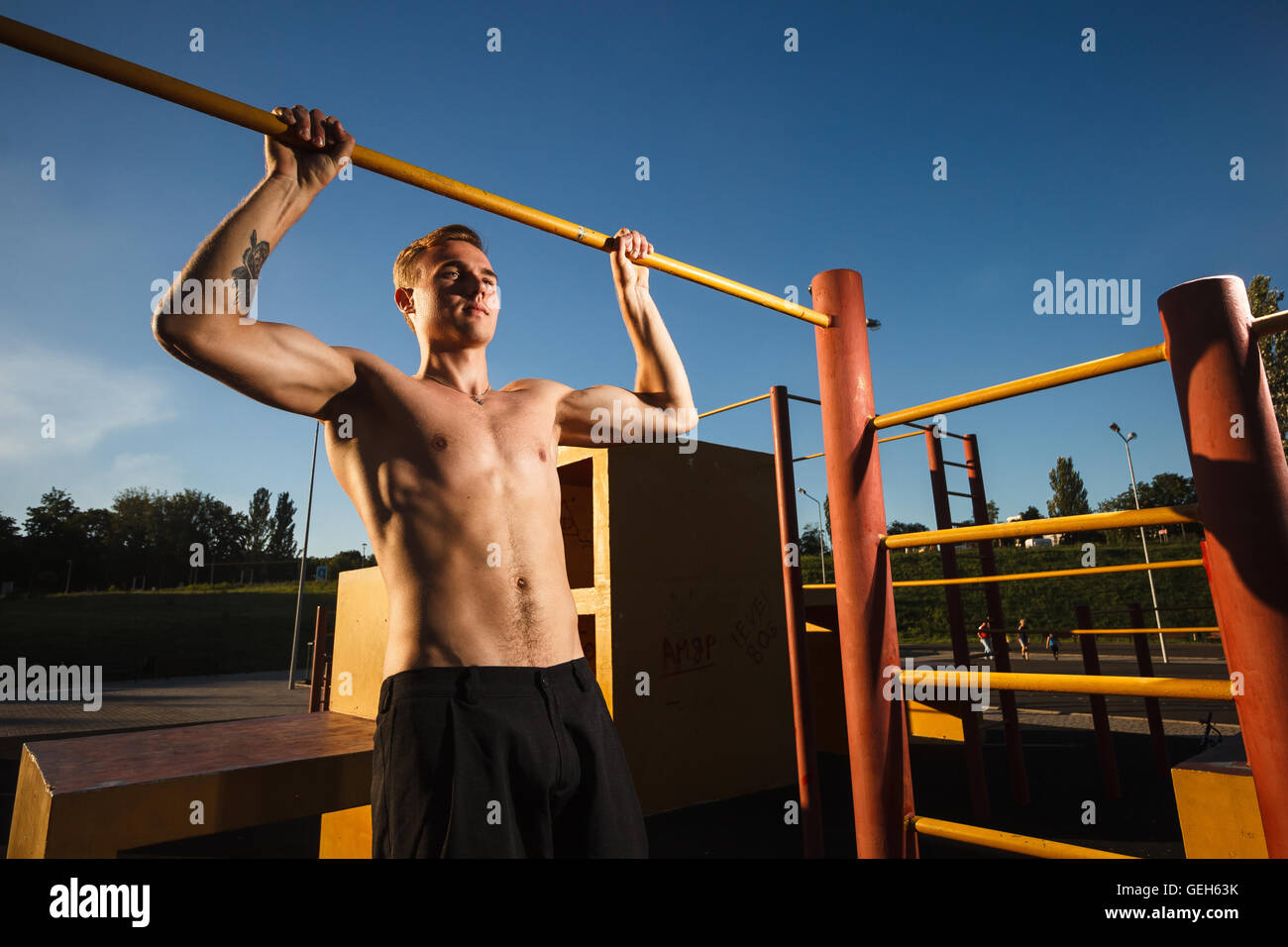 Young fit shirtless man exercising on outdoor sports ground. Concept: healthy lifestyle Stock Photo