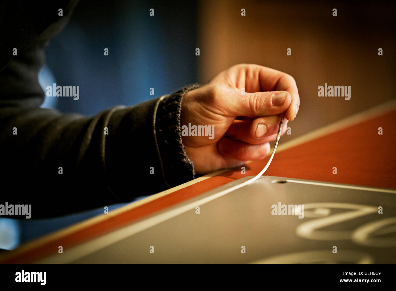 A sign writer working with a loaded brush painting a line freehand on ...