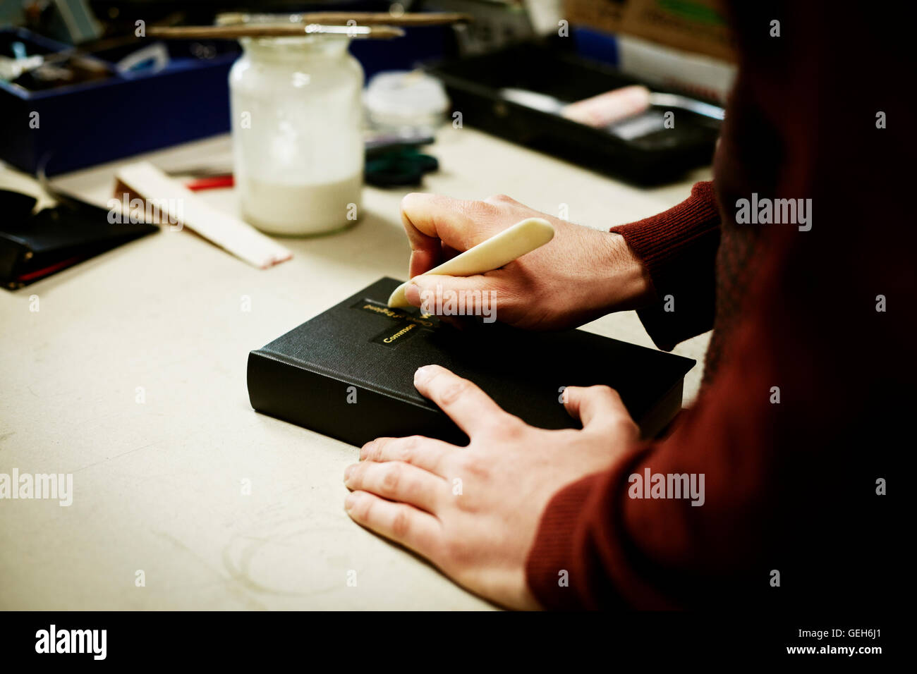 A man using a small handheld tool on the cover of a book. Stock Photo