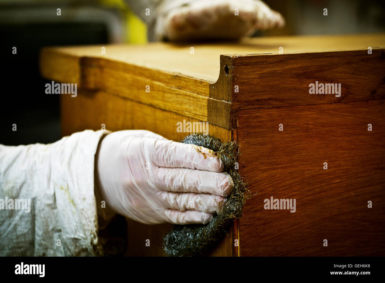 A person in gloves using wire wool to sand down or wax a piece of furniture. Stock Photo