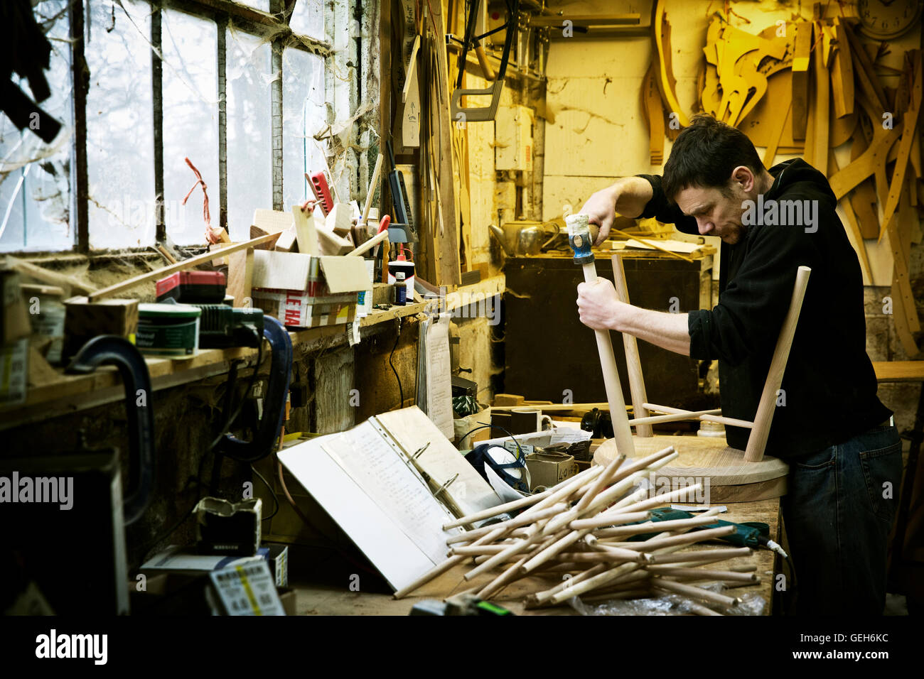 A man working in a furniture maker's Windsor chairs Stock