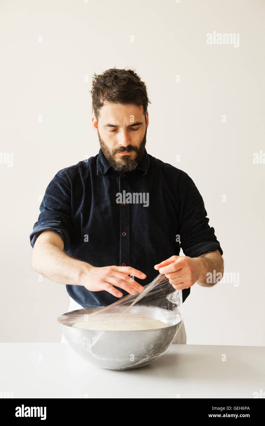 https://c8.alamy.com/comp/GEH6PA/baker-covering-bread-dough-in-a-metal-bowl-with-cling-film-GEH6PA.jpg